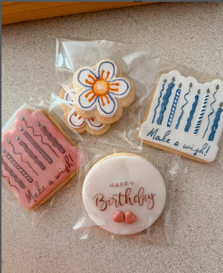 Hand-decorated birthday cookies in pink, blue, white and orange icing.